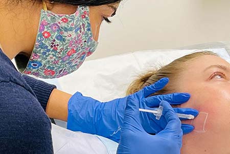 Cosmetic doctor during an anti wrinkle treatment on a female patient’s face