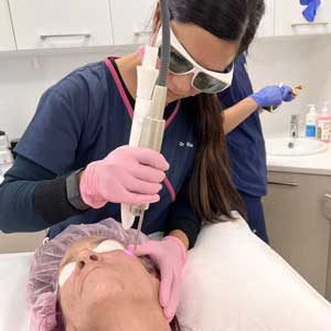 Cosmetic doctor uses Fotona skin laser treatment for facial skin tightening of a patient